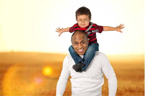 smiling dad with small child on shoulders pretending to be an airplane